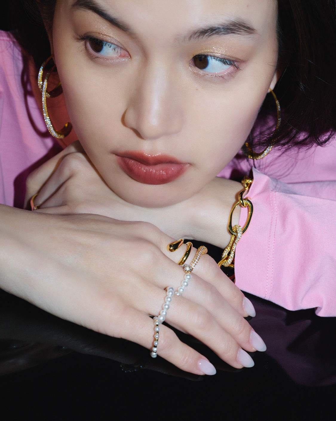 メタル素材にクリスタルが施されたアクセを複数つけた女性